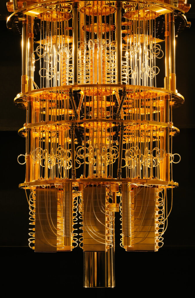 Intérieur d'un ordinateur quantique montrant une structure cylindrique complexe dorée avec de multiples câbles et étages, sur un fond noir.
